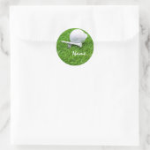 Golfbal en t-shirt op groen gras ronde sticker (Tas)