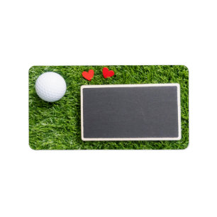 Golfbal met twee harten zijn op groen met plank etiket