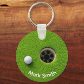 Golfbal naast hole op groene gras golfbaan sleutelhanger (Voorkant)