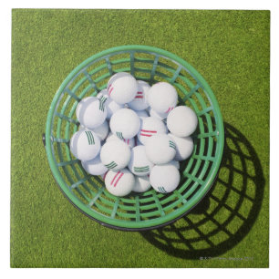 Golfballen in een mand die op korte groene tegeltje
