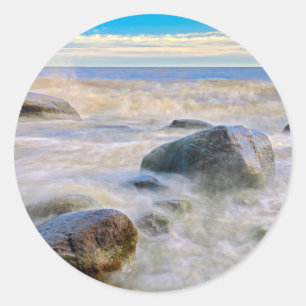 Golven die op rotsen aan de kust slaan ronde sticker