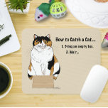 Grappige Beige Calico Kat Doos Humor Vangst Muismat<br><div class="desc">Deze grappige katillustratie toont een ontspannen schildpadkat die in een zeer kleine kartonnen doos zit tegen een zachte beige achtergrond, gekoppeld aan de humoristische zin “Hoe je een kat vangt.” Geïnspireerd door klassiek katachtig gedrag, legt het ontwerp de onweerstaanbare aantrekkingskracht vast die dozen hebben voor katten overal. De eenvoudige compositie...</div>