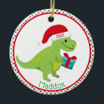 Green Dinosaur met Santa Hat Personalized Keramisch Ornament<br><div class="desc">Cute green dinosaur draagt een rode kersthoed en draagt een blauw cadeau. De rand is rode en groene poka stippen. Geef je kinderen een persoonlijk tintje op de onderkant en het jaar op zijn pet. Achterzijde is hetzelfde ontwerp.</div>