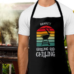 Grillen en koelen gepersonaliseerd schort<br><div class="desc">Zwart gepersonaliseerd schort is voorzien van een BBQ grill op strepen met de woorden "Grilling and Chilling". Perfect cadeau voor vaderdag of voor zijn verjaardag.</div>