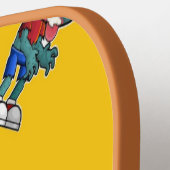 Groen zombie-kind op sinaasappel pickleball paddle (Links Detail)
