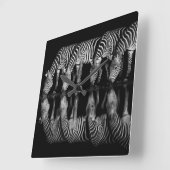 Groep vlaktezebra's drink 's nachts samen vierkante klok (Hoek)