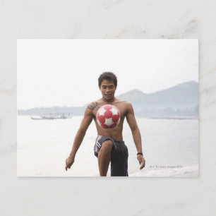 Guy die football speelt op het strand briefkaart