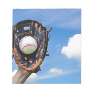 Hand die honkbal houdt in handschoen met blauwe lu notitieblok