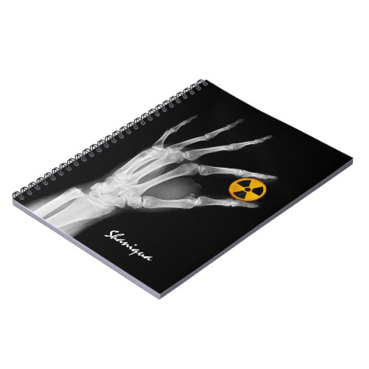 Handje dat een radiatiesymbool vasthoudt notitieboek (Linkerzijde)
