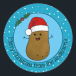 Happy kerstaardappel op maat ronde sticker<br><div class="desc">Happy Christmas Potato met een rode kerstmuts met een witte bontrand en een witte donzige pompom. Zijn lichaam is bruin met kleine zwarte stippen en een grote vrolijke glimlach. Hij heeft stokken voor armen en houdt groene holle bladeren met rode bessen. Achter hem is een blauwe achtergrond met witte sprankelende...</div>