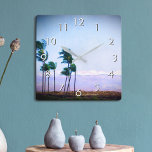 Hawaii palmboom Paarse landschap foto stijlvol Vierkante Klok<br><div class="desc">U waardeert de schoonheid van de natuur wanneer u de tijd op deze blauwe en paarse, zacht verlichte fotografische wandklok van palmbomen die in de Hawaiiaanse bries blazen tegen een bergachtergrond controleert. Uw keuze uit een rond of vierkant klokgezicht. Maakt een geweldig cadeau voor het huishouden! U kunt deze muurklok...</div>