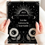 Hemelse Zon Maan Sterren Custom Manifestatie Planner<br><div class="desc">Dit fascinerende ontwerp beschikt over hemelse elementen zoals de zon, maan, sterren en bloeiende zonnebloemen, allemaal tegen een gedurfde zwarte achtergrond. De motivatie zin "Laat het universum je gids zijn" inspireert focus en manifestatie, waardoor dit ontwerp zowel functioneel als empowerend is. Gepersonaliseerd met een aangepaste naam en jaar, is het...</div>