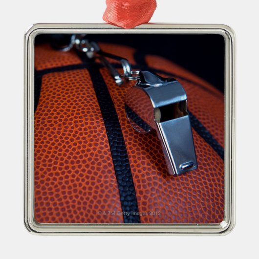 Het fluitje van een scheidsrechter ligt bovenop ee metalen ornament (Voorkant)