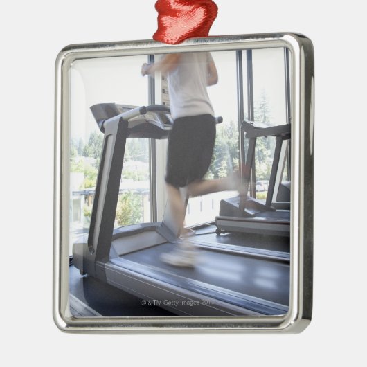 Jong man dat op een loopband in de gezondheidsclub metalen ornament (Links)