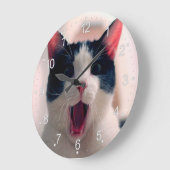 Jonge, gekke verraste kat die grote ogen trekt grote klok (Hoek)