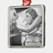 Jonge vrouw die op het bed ligt en de lamp uitzet metalen ornament (Links)