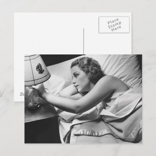 Jonge vrouw liggend op bed die lamp afzetten briefkaart (Voorkant / Achterkant)
