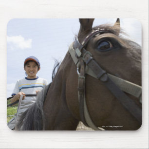 Jongen die op een paard rijden muismat