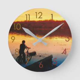 Jongen op fiets bij zonsondergang wandklok