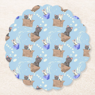 Katten in doos en melkdruppels op blauw kartonnen onderzetters