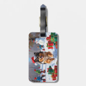 Keeshond-hond loopt in de sneeuw met kerstmuts bagagelabel (Achterkant verticaal)
