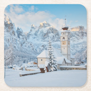 Kerk bedekt met sneeuw met bergachtige achtergrond kartonnen onderzetters