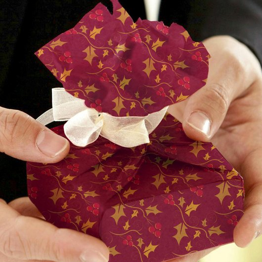 Kerst gouden hulst en rode bessen op diep rood tissuepapier