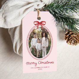 Kerstfoto met vintage rode strik en roze achtergro cadeaulabel