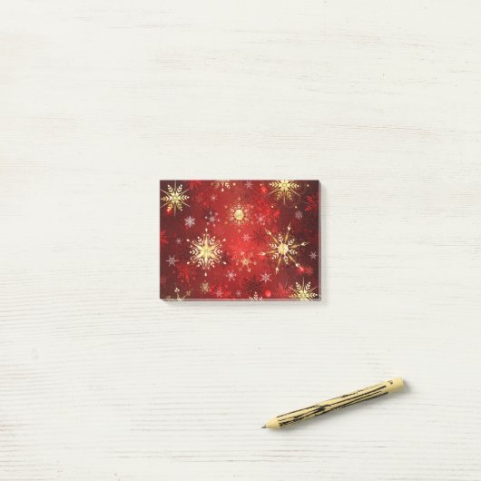 Kerstgouden sneeuwvlokken op rode achtergrond post-it® notes (Op bureau)