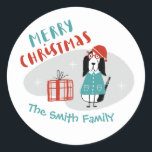 Kersthond op maat ronde sticker<br><div class="desc">Kute hound-tekenfilmhond,  met een blauw sweater en rood gebreid pet met een geschenk rond rode doedels. Stel je voor op een moderne,  moderne stijlwolkenachtergrond met witte sneeuwvlokken in de beginstijl. Vrolijk kerstfeest in bijpassend blauw en rood lettertype. Pas uw bericht aan in een blauw lettertype.</div>