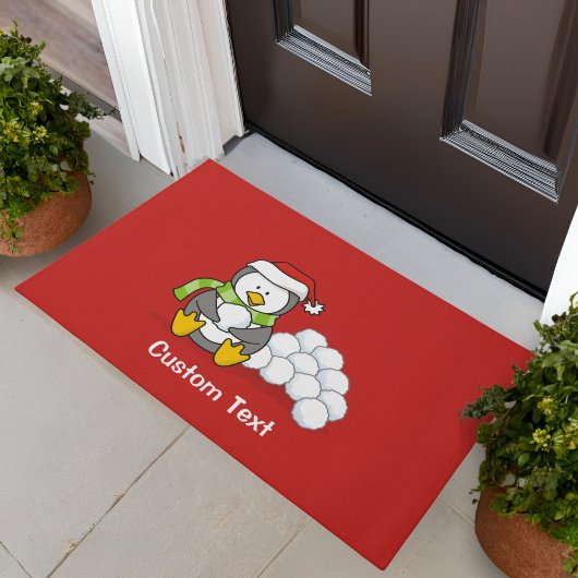 Kerstpinguïn zittend met sneeuwballen deurmat