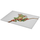 Kikte groene kikker met oogbril op wit snijplank (Hoek)