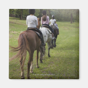 Kleine meisjes die met paarden rijden magneet