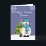 Kleinzoon Snowman Kerst Kaart<br><div class="desc">Vier Kerstmis met je kleinzoon met deze schattige kaart met een sneeuwpop met een blauwe sjaal,  wanten en pet met een sterretje en een versierde kerstboom achter hem. Hij staat in de sneeuw met een donkerblauwe achtergrond en een grote sneeuwvlok bovenaan elke kant.</div>