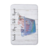 Kleurrijk gevouwen wasgoed op hanen in een blauwe  badmat (Voorkant Verticaal)