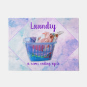 Kleurrijk gevouwen wasgoed op hanen in een blauwe  deurmat (Voorkant)