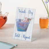 Kleurrijk gevouwen wasgoed op hanen in een blauwe  reclamebord met voetstuk (Insitu)