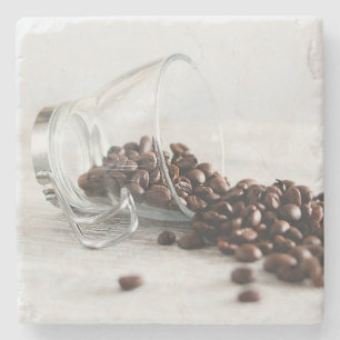 Koffiebonen die uit een duidelijke Koffiebeker lop Stenen Onderzetter