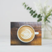 Koffielatte met bladschuim op hout briefkaart (Staand voorkant)
