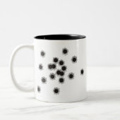 Kogelopeningen van een geweer of pistool, eventuee tweekleurige koffiemok (Links)