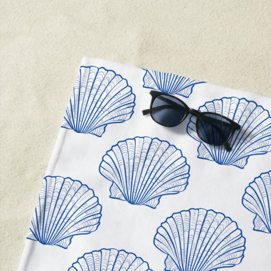 Kustblauwe schelp op het witte monogram strandlaken (In situ)