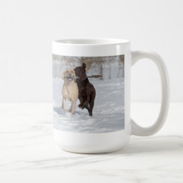 Labrador Retrievers speelt in de sneeuw. Koffiemok