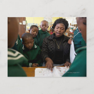 Leraar assisteert een groep leerlingen in de briefkaart