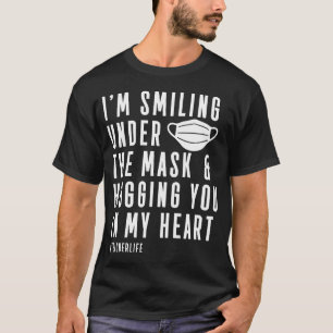 Leraar glimlachend onder masker knuffelen in hart t-shirt