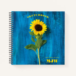 Levendige zonnebloem en monogram op blauwe achterg notitieboek