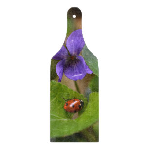 Lieveheersbeestje op zoete viooltjesbloemen snijplank