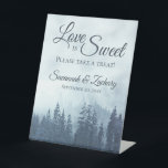 Love is Sweet Misty Blue Pine Trees Rustic Wedding Reclamebord Met Voetstuk<br><div class="desc">Dit mooie voetstuk is perfect voor een tafel bij je trouwreceptie. Het bijtende buitenontwerp is voorzien van een bergzijde bedekt met blauwe sparren of pijnbomen en gehuld in mist of nevel. De elegante manuscripttekst leest "de Liefde is lief te nemen gelieve een behandeling"met ruimte voor de namen van het paar...</div>
