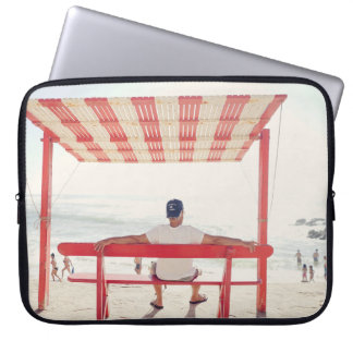 Man op een bank bij het strand laptop sleeve