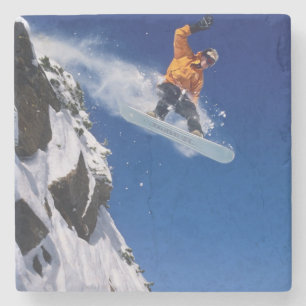 Man op een snowboard die van een richel springt bi stenen onderzetter