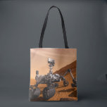 Mars Science Laboratory Curiosity Rover. Tote Bag<br><div class="desc">Het concept van Mars Science Laboratory Curiosity rover is een mobiele robot die het cadeau van Mars onderzoekt. In dit afbeelding onderzoekt de rover een rots op Mars met een set gereedschappen aan het uiteinde van de arm van de rover, die ongeveer 7 voet uitstrekt. Twee instrumenten op de arm...</div>